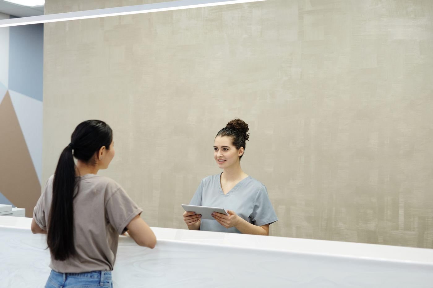 Clinic receptionist speaking with a client at the front desk